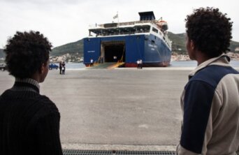 migrants wait to board a ferry