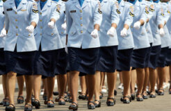 Women in uniform march during a ceremony