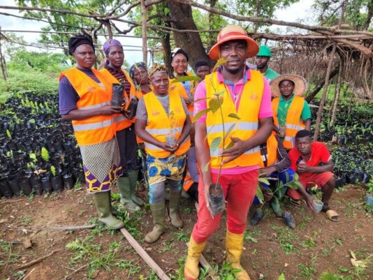 Sunday Geofrey holds a sapling in the solar-powered tree nursery