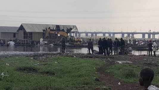 Makoko residents watch excavator bringing down wooden structures