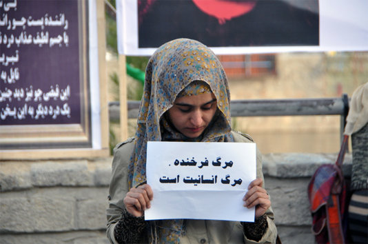 A girl carrying a card that says: \'The death of Farkhunda was the death of humanity\'.