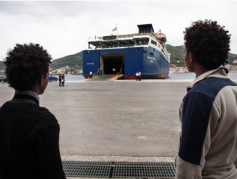 migrants wait to board a ferry