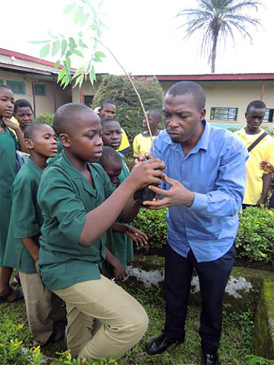 Green Cameroon\'s Executive Director Masango Sone handing trees to students for onward planting