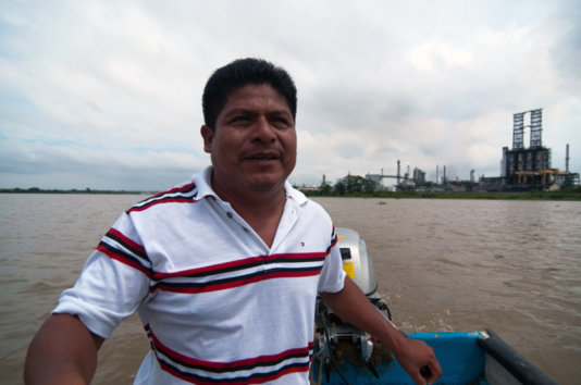 Juan Luis Francisco in a boat on the Coatzacoalcos river with the pet coke processing plant behind him. Juan Luis Francisco in a boat on the Coatzacoalcos river with the pet coke processing plant behind him.