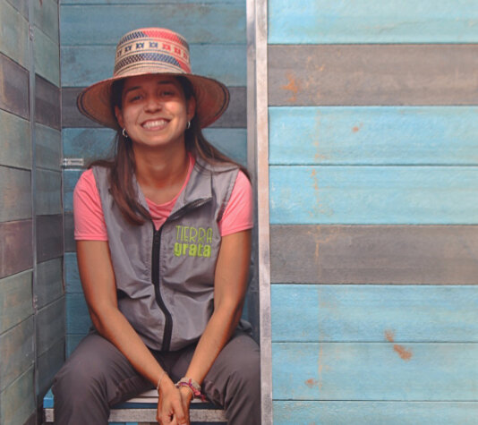 Jenifer Colpas, a founder of Tierra Grata, is inside the ecological toilet that the organization provides. Jeni-bano