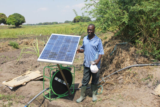 Farmer standing next to a solar water pump.