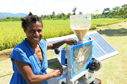 Woman using a solar rice mill.