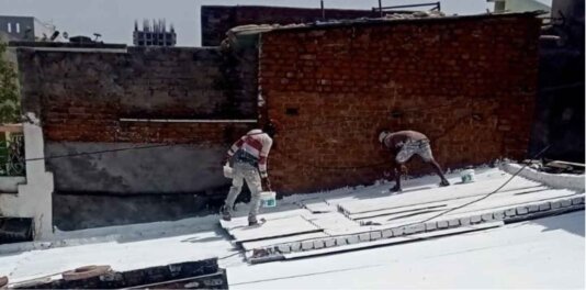 Men applying white reflective paint that helps reduce indoor temperatures.