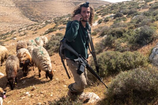 An armed settler approaching Palestinian shepherds near the Havat Ma’on settlement in Masafer Yatta, West Bank. An armed settler approaching Palestinian shepherds near the Havat Ma’on settlement in Masafer Yatta, West Bank.